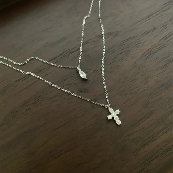 Cadena estilo layering con dije de cruz y dije de luz con baño de oro blanco