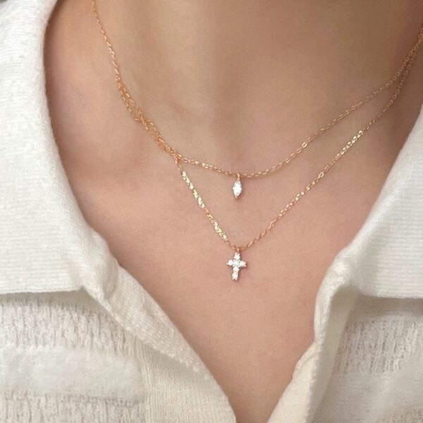 Cadena estilo layering con dije de cruz y rombo de punto de luz, baño de oro de 18K